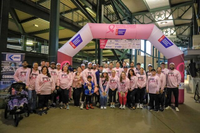 Kpost Team posing under American Cancer Society Group arc