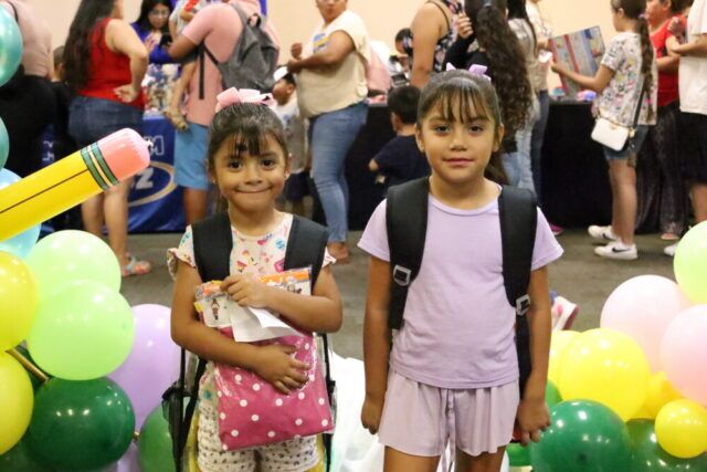Kids posing with new backpacks at backpack charity event